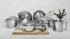 Foto do Jogo de Panelas Tramontina Solar em aço inox com 6 peças exibido sobre uma tábua de madeira em uma cozinha branca