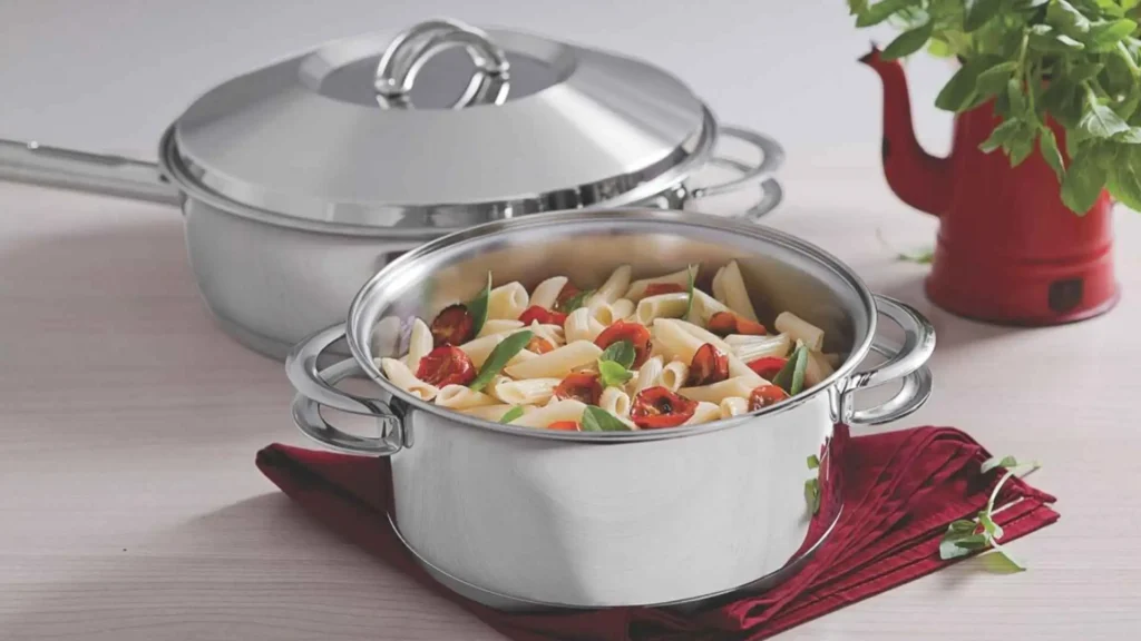Caçarola do Jogo de Panelas Tramontina Solar 6 Peças com macarrão e vegetais, destacando o brilho do aço inox e a tampa de vidro