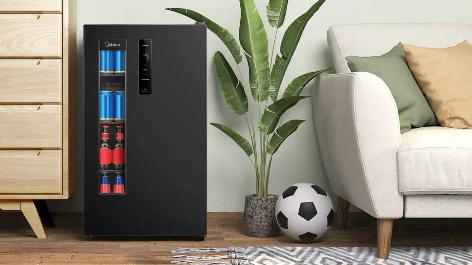 Cervejeira Midea 82L preta instalada em uma sala de estar moderna ao lado de um sofá e planta decorativa