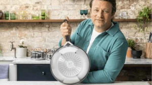 Chef Jamie Oliver segurando a base da frigideira Tefal em aço inox, destacando o fundo triplo para indução