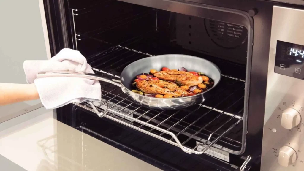 Frigideira Tramontina Grano de aço inox com peixe sendo levada ao forno para finalizar o cozimento