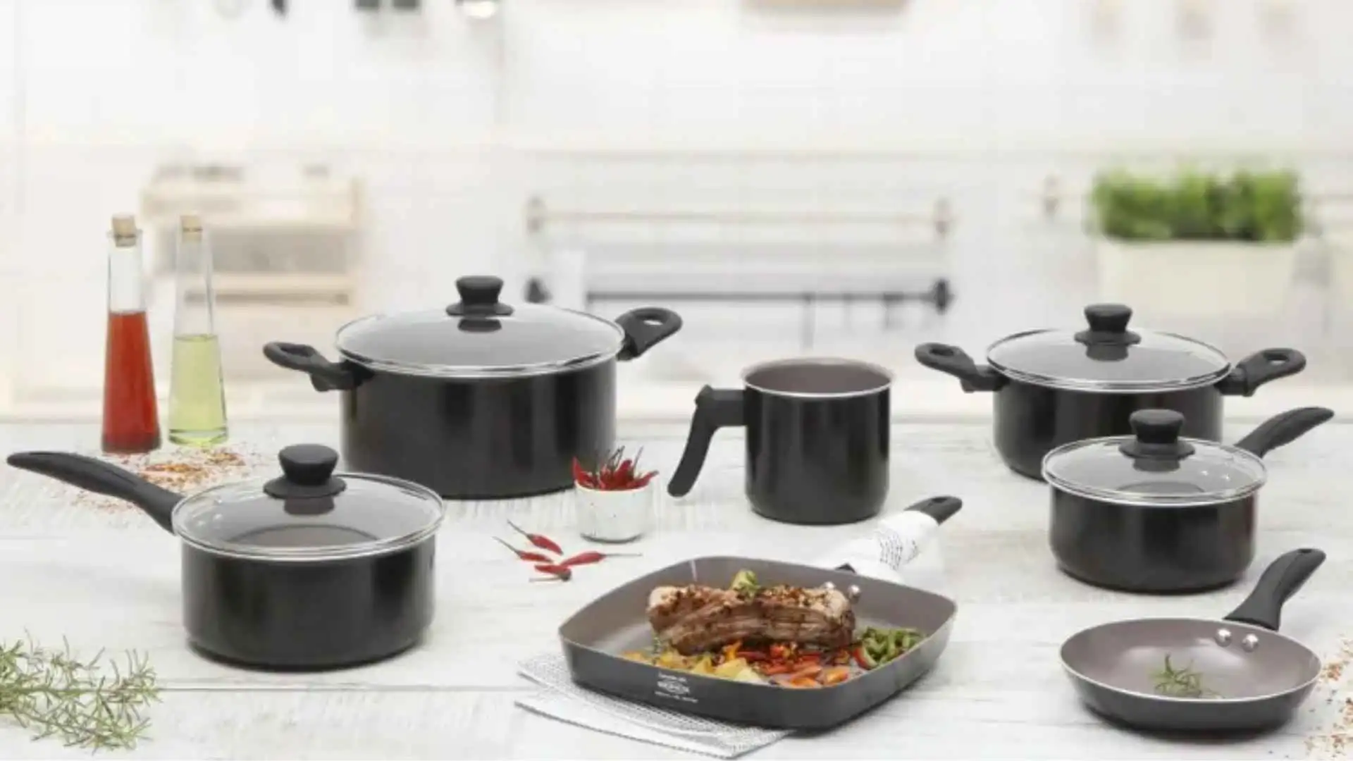 Jogo de panelas Brinox Ceramic Life Easy na cor preta dispostas sobre uma bancada de cozinha com alimentos