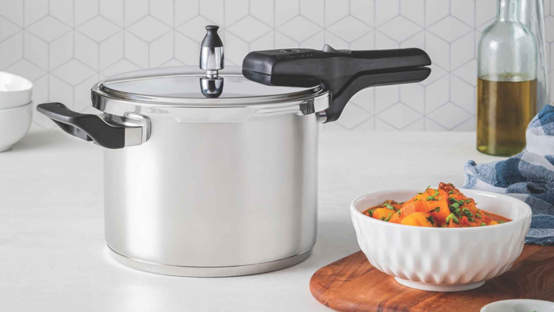 Panela de pressão Tramontina Brava em cima de uma bancada de cozinha ao lado de um bowl com alimentos