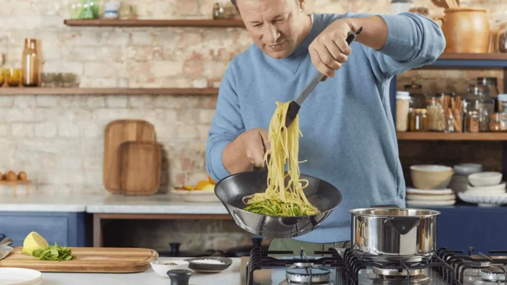 Pessoa preparando massa em uma frigideira Wok de aço inox Tefal Jamie Oliver sobre fogão a gás