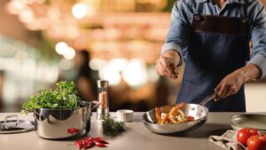 Frigideira Tramontina Grano em aço inox com corpo triplo sendo utilizada para cozinhar vegetais no fogão