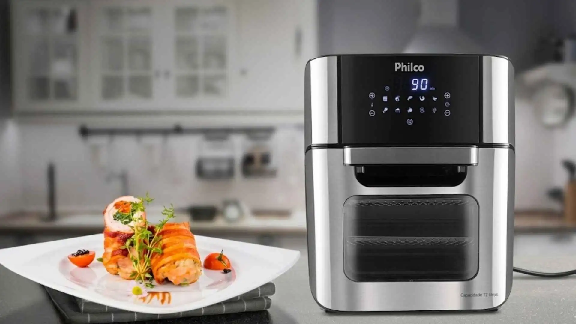 Air Fryer Oven Philco 12L PFR2200 preta com acabamento em inox sobre bancada de cozinha com prato de salmão à frente