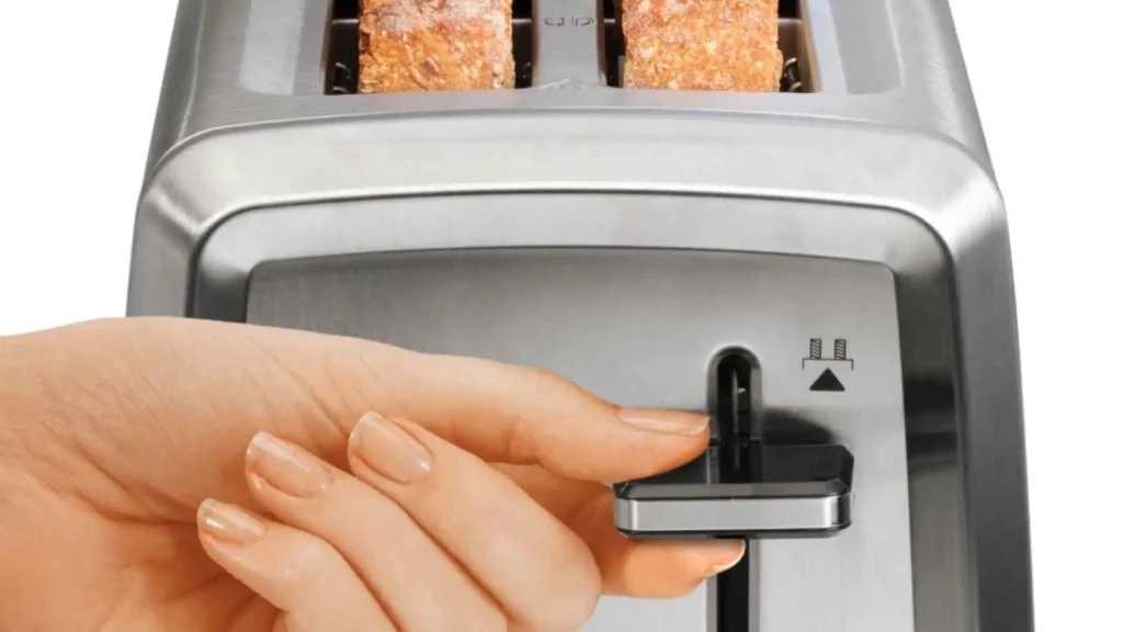 Detalhe da mão de uma pessoa acionando a alavanca de elevação extra da Torradeira Elétrica Hamilton Beach