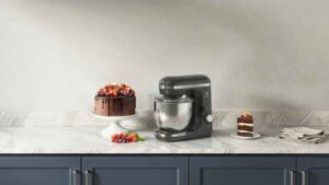 Batedeira Planetária Electrolux Experience EKM40 cinza em uma bancada de mármore ao lado de um bolo de chocolate confeitado