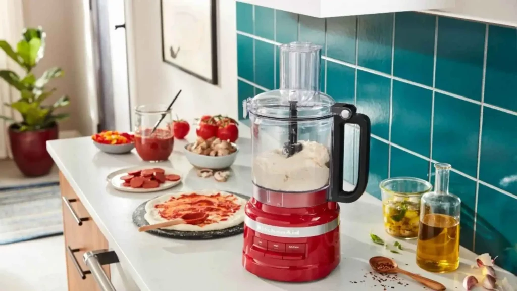 Design do processador KitchenAid Empire Red posicionado em uma bancada de cozinha moderna com azulejos azuis