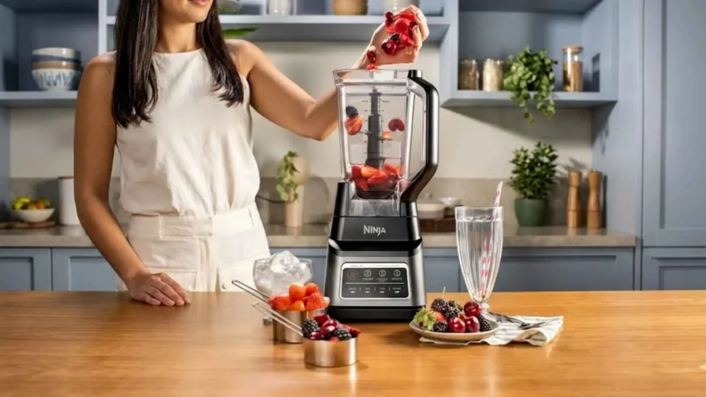 Close-up de uma pessoa colocando frutas vermelhas na jarra do Liquidificador Ninja Standalone Professional Plus