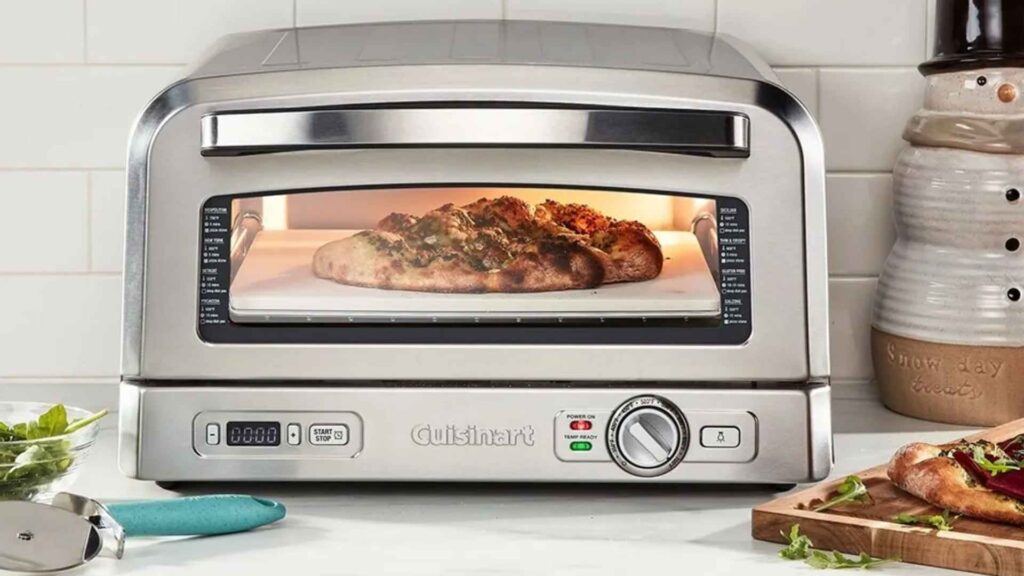 Forno de pizza Cuisinart CPZ-120BR ligado em bancada de cozinha mostrando uma pizza assando através do visor amplo