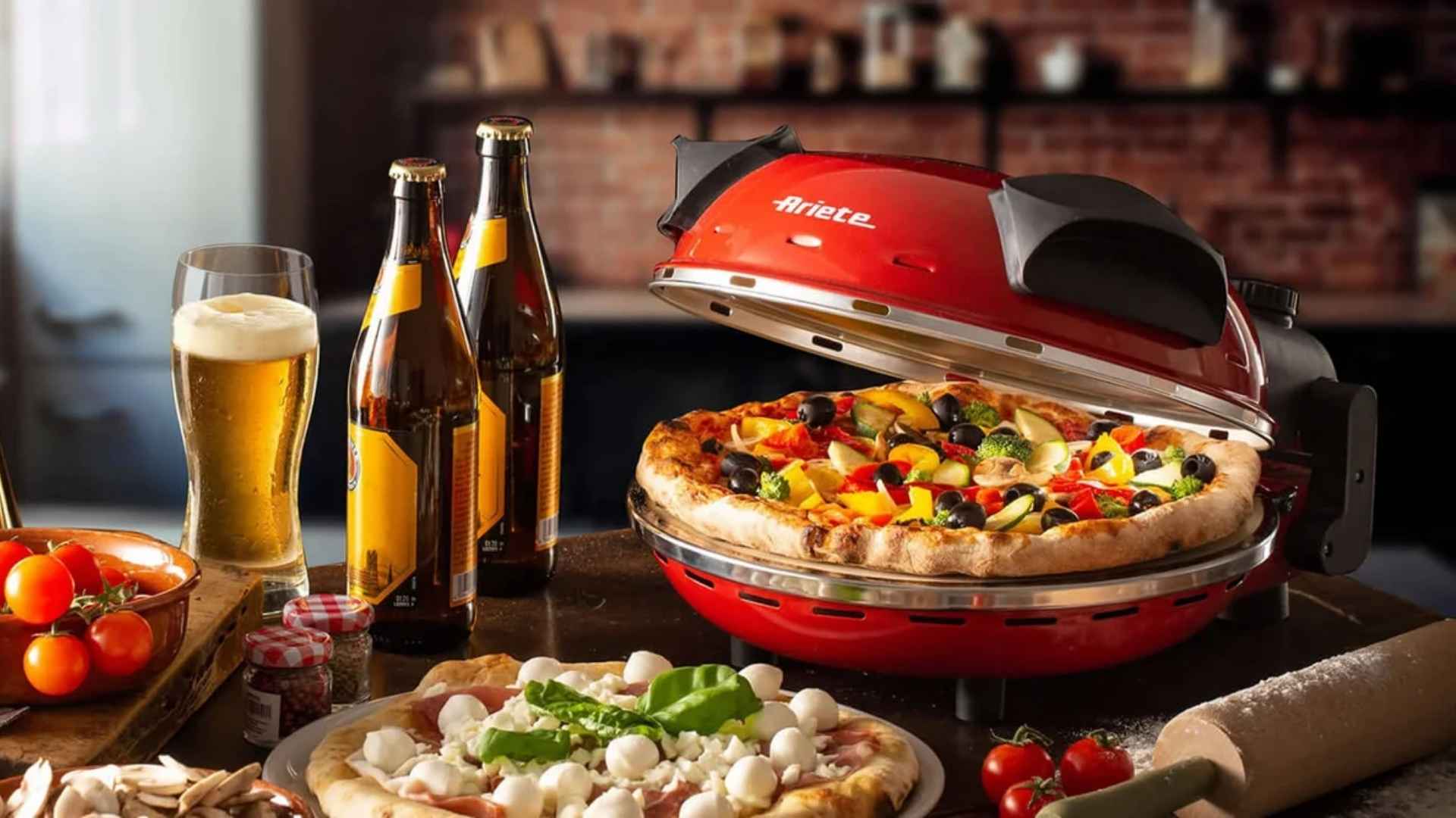 Forno de pizza elétrico Ariete 909 vermelho sobre uma bancada de madeira com ingredientes de pizza ao redor