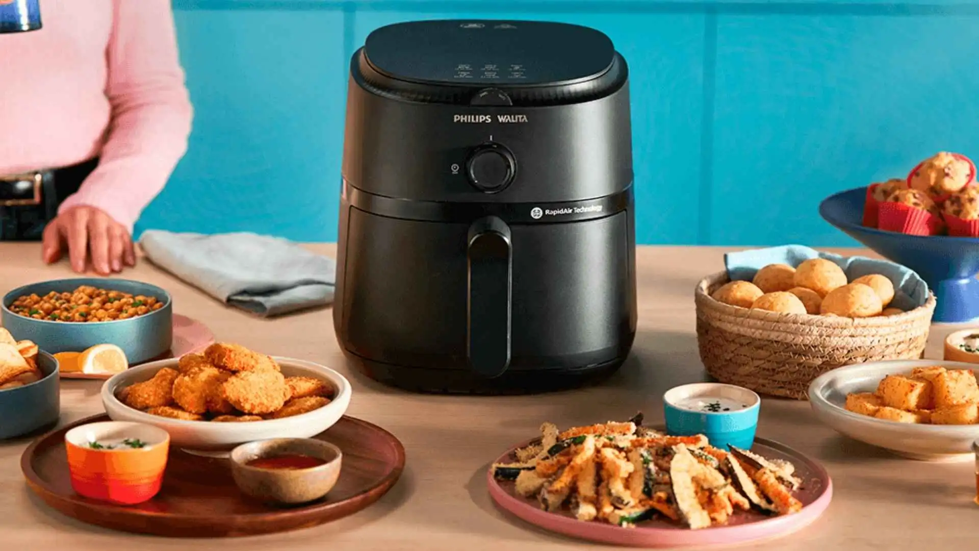 Fritadeira Airfryer Philips Walita Série 1000XL preta em cima de uma mesa de café da manhã com alimentos diversos