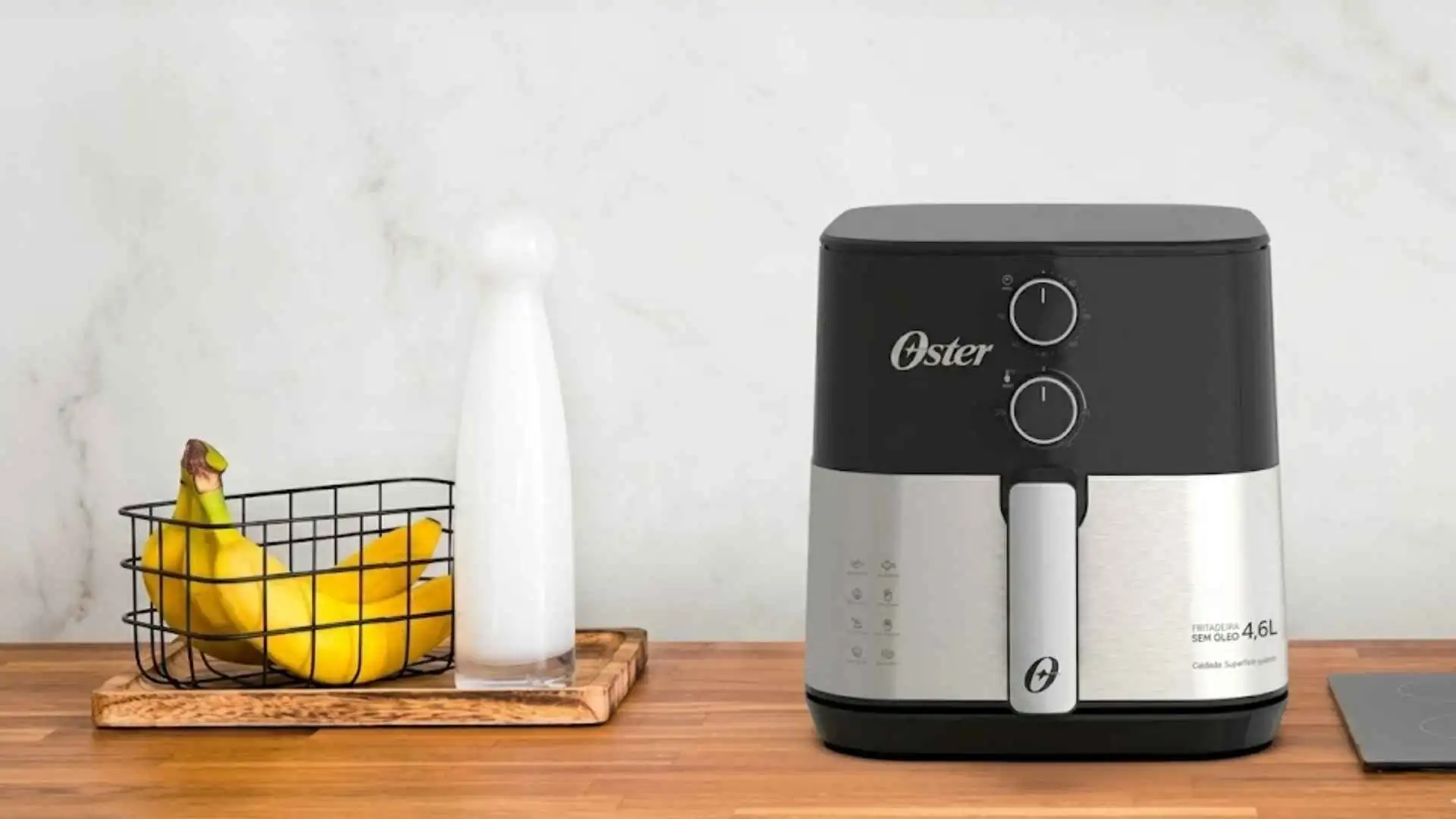 Fritadeira sem óleo Oster OFRT520 em acabamento inox sobre uma bancada de madeira na cozinha
