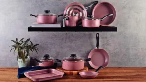 Jogo de panelas Tramontina Linz 10 peças na cor pink com revestimento antiaderente Starflon Max e tampas de vidro temperado sobre uma bancada de madeira