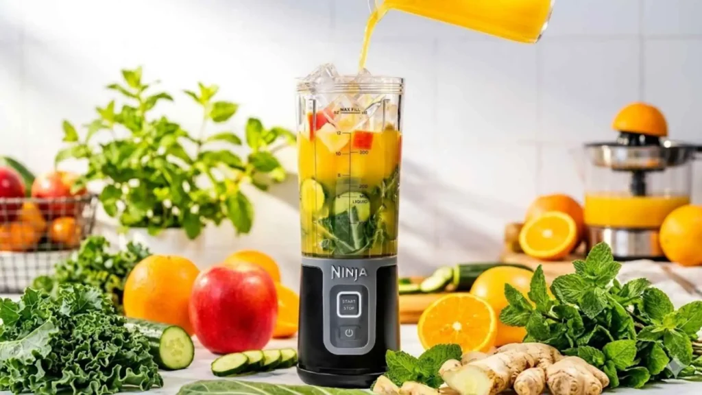 Ninja Blast Liquidificador Portátil Bivolt sendo preenchido com suco de laranja, maçã e vegetais para um preparo detox