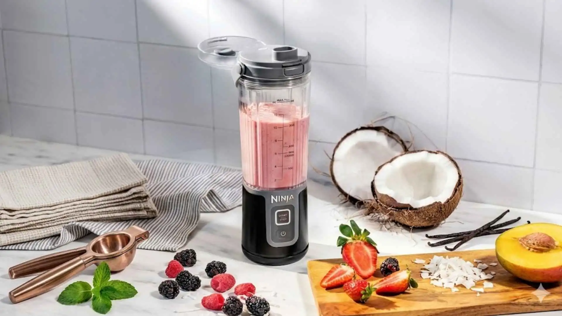 Ninja Blast Liquidificador Portátil Bivolt batendo vitamina de frutas tropicais ao lado de coco e frutas vermelhas