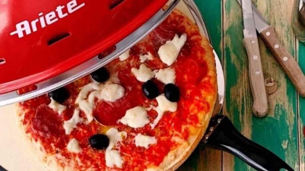 Detalhe de uma pizza de calabresa com queijo derretido sendo assada sobre a pedra refratária do forno Ariete 909