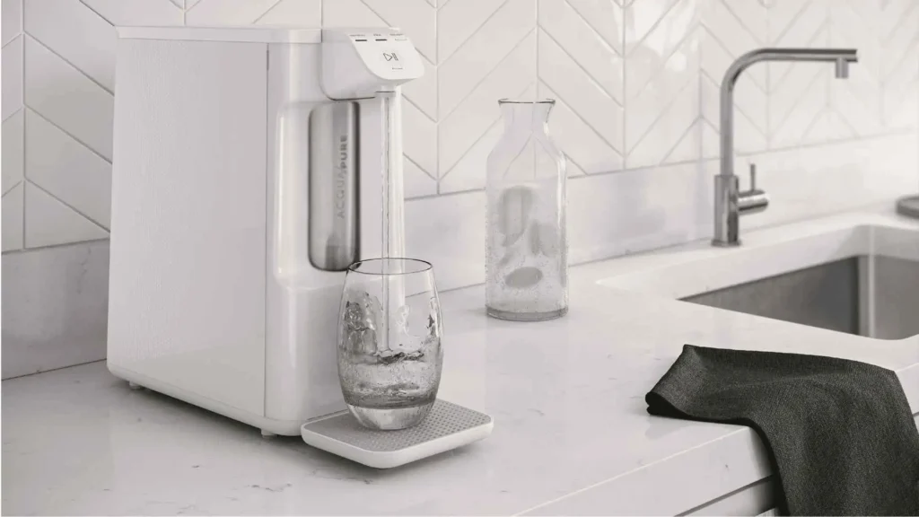 Purificador de água Electrolux PE12B branco posicionado ao lado de uma pia de cozinha, demonstrando praticidade de instalação