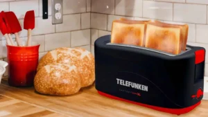 Torradeira Telefunken Easytoast 5000 XL preta e vermelha sobre bancada de madeira com pães ao lado
