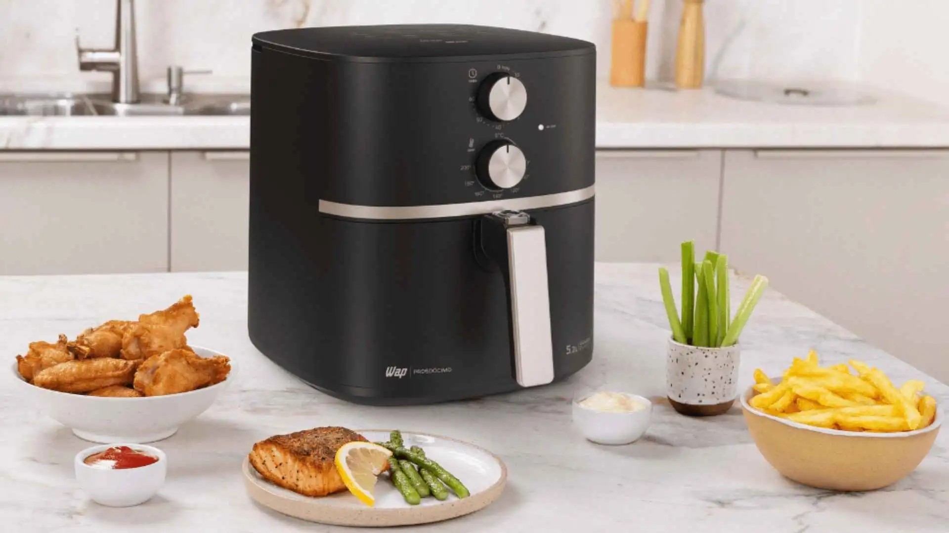 Fritadeira elétrica WAP Air Fryer Grand Family 5,2L preta fechada sobre bancada de cozinha com acompanhamentos
