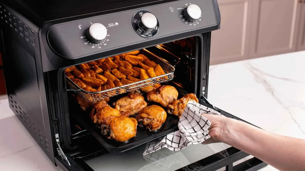 Bandeja Fryer do Air Forno Mueller 35L sendo retirada com porções de empanados crocantes e batatas fritas