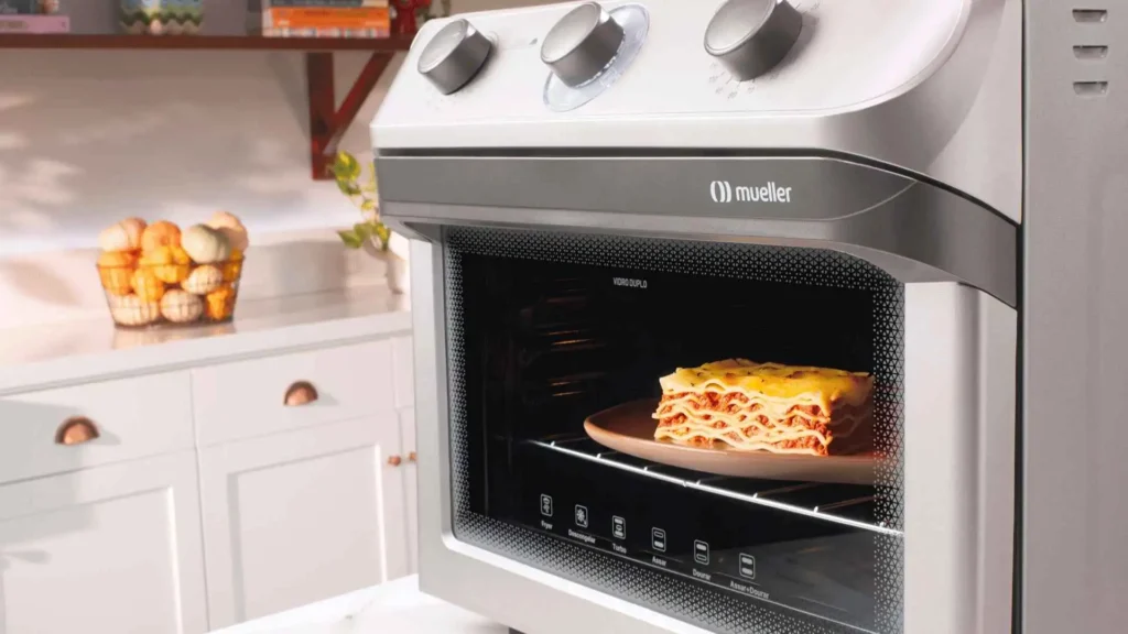 Air Forno Mueller 35L prata em uma cozinha moderna preparando uma lasanha gratinada