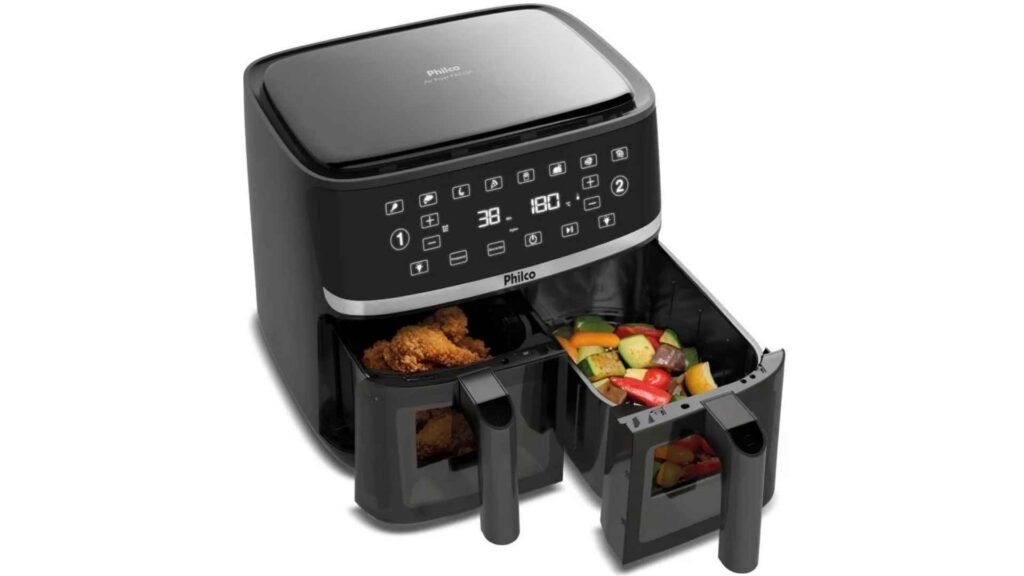 Foto em ângulo diagonal da Air Fryer Philco PAF10A com as duas gavetas de 5 litros abertas, mostrando carne assada de um lado e legumes coloridos do outro