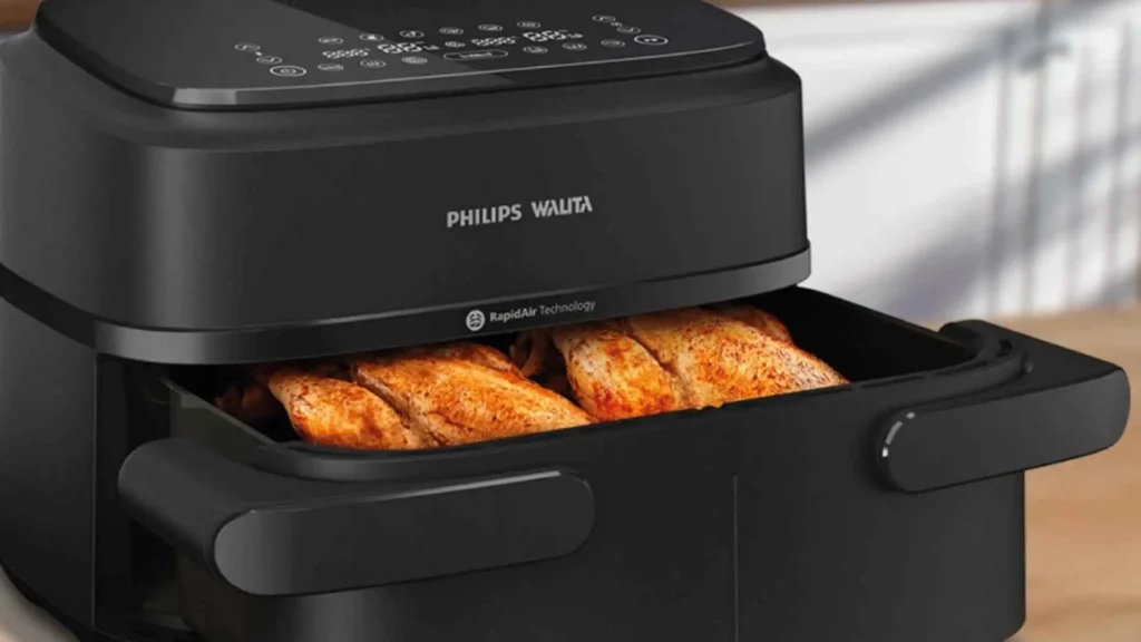 Alimentos sendo preparados dentro do cesto aberto da Fritadeira Airfryer Philips Walita Série 1000 Duplo Cesto 7,1L Preta NA150
