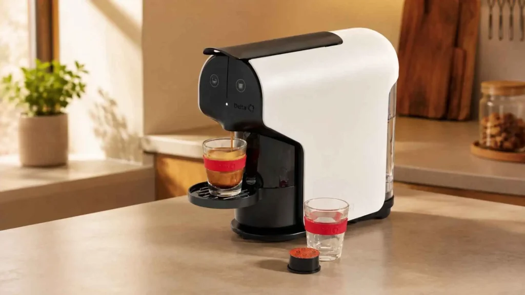 Cafeteira de cápsulas Delta Q Quick branca sobre bancada de cozinha iluminada