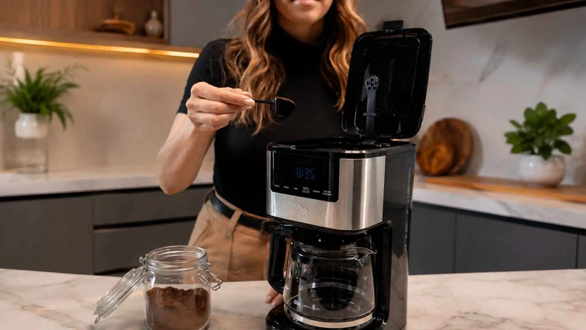 Mulher adicionando pó com colher dosadora no filtro permanente da Cafeteira Digital Aroma WAP WCD 1500 na bancada