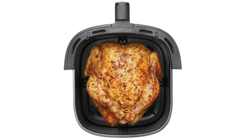 Visão superior de um frango inteiro dourado e assado dentro do cesto quadrado de 5 litros da Air Fryer Digital Hamilton Beach 5L.