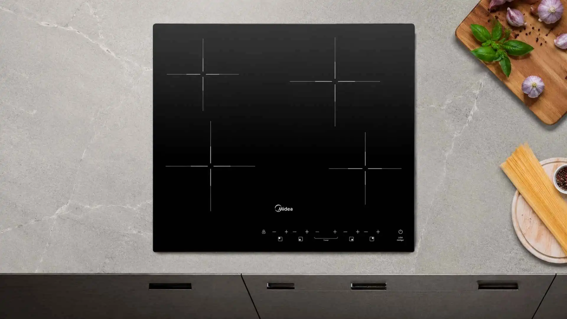 Vista superior de um cooktop 4 bocas Midea CCB40P2 vitrocerâmico embutido em uma bancada de cozinha planejada cinza clara ao lado de ingredientes culinários