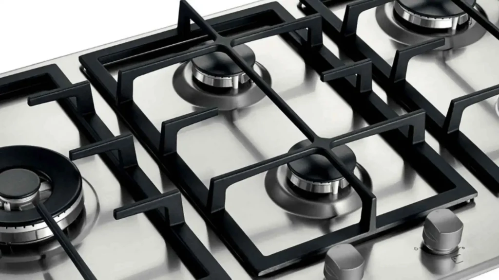 Visão aproximada das grades de ferro fundido pesadas e estáveis do Cooktop 5 Bocas Brastemp BDK90DR sobre a mesa de inox