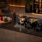 Visão ampla de uma cozinha planejada moderna com o Cooktop 5 Bocas Electrolux Pro Series KE5PS embutido em uma bancada de granito escuro iluminada