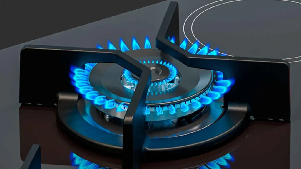 Queimador tripla chama do cooktop 5 bocas Fischer 7730 ligado com chamas azuis acesas sobre a trempe de ferro fundido