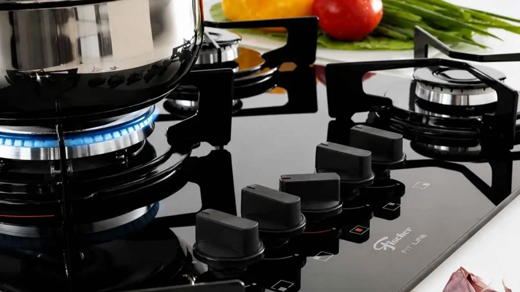 Detalhe aproximado do acendimento do queimador tripla chama e das trempes de ferro fundido do cooktop a gás Fischer 5 bocas Fit Line