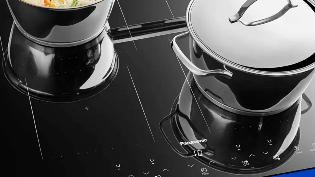 Panelas de aço inox posicionadas sobre as zonas de aquecimento do Cooktop de Indução Panasonic KY-W648CLRPK em funcionamento