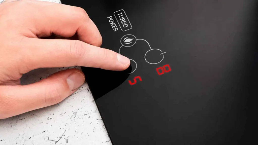 Dedo tocando no painel Touch digital do cooktop de indução EOS ECI05EP para ajustar o nível de potência