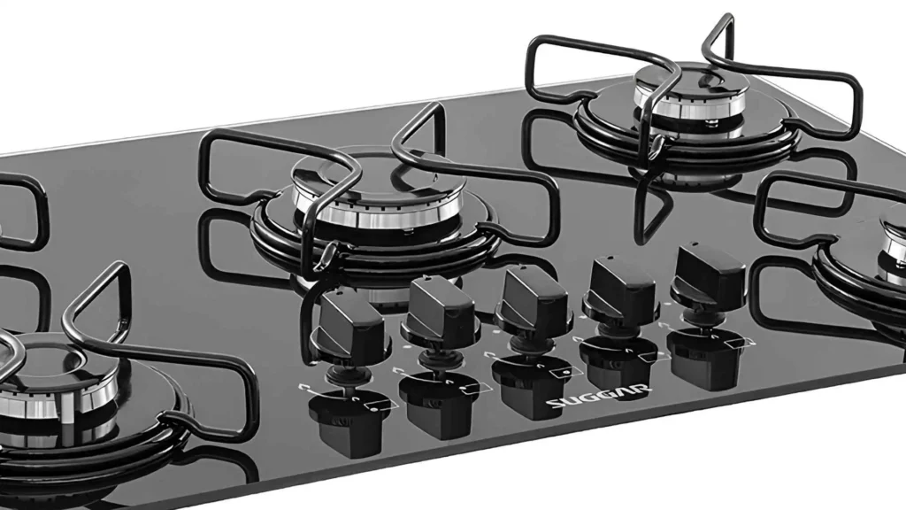 Detalhe aproximado dos queimadores a gás e dos botões laterais removíveis do cooktop Suggar 5 bocas vidro FG5005AVP