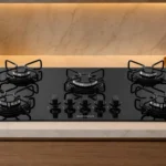 Cooktop Suggar 5 bocas de vidro temperado preto FG5005AVP instalado em uma bancada de cozinha moderna com iluminação embutida