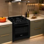Fogão de embutir Venax Gaudi Prisma Vítreo preto instalado em uma bancada de cozinha planejada moderna com armários verdes