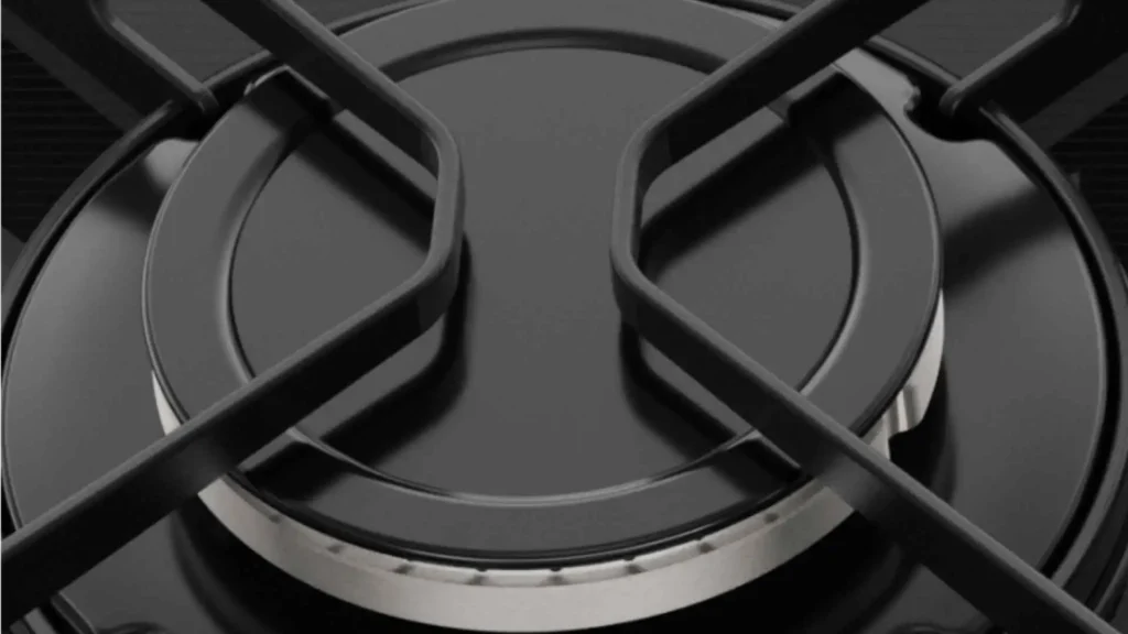 Detalhe aproximado de uma boca de fogão com grade individual de ferro fundido preto sobre mesa de vidro temperado Electrolux