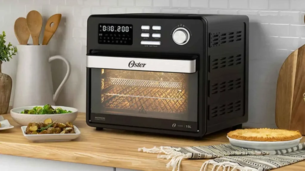 Forno e Fryer 15L Oster 10 em 1 preto em uma bancada de cozinha com acessórios ao lado