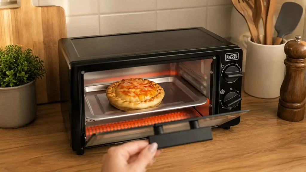 Porta aberta do forno elétrico Black+Decker FT9N 800W mostrando uma mini pizza assando na grelha