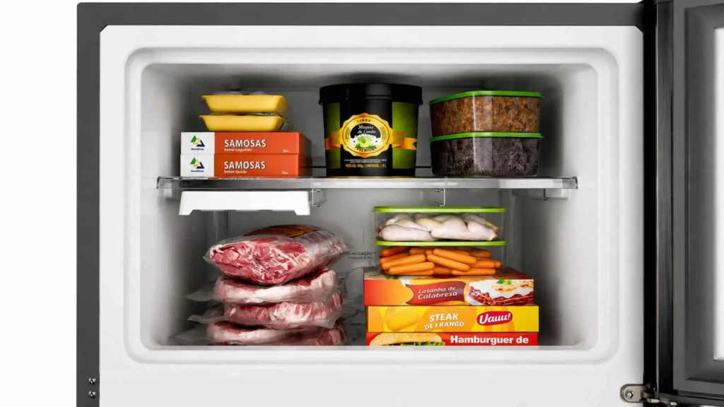 Interior do freezer espaçoso de 73 litros da geladeira Consul Frost Free CRM40MK com alimentos e carnes congeladas