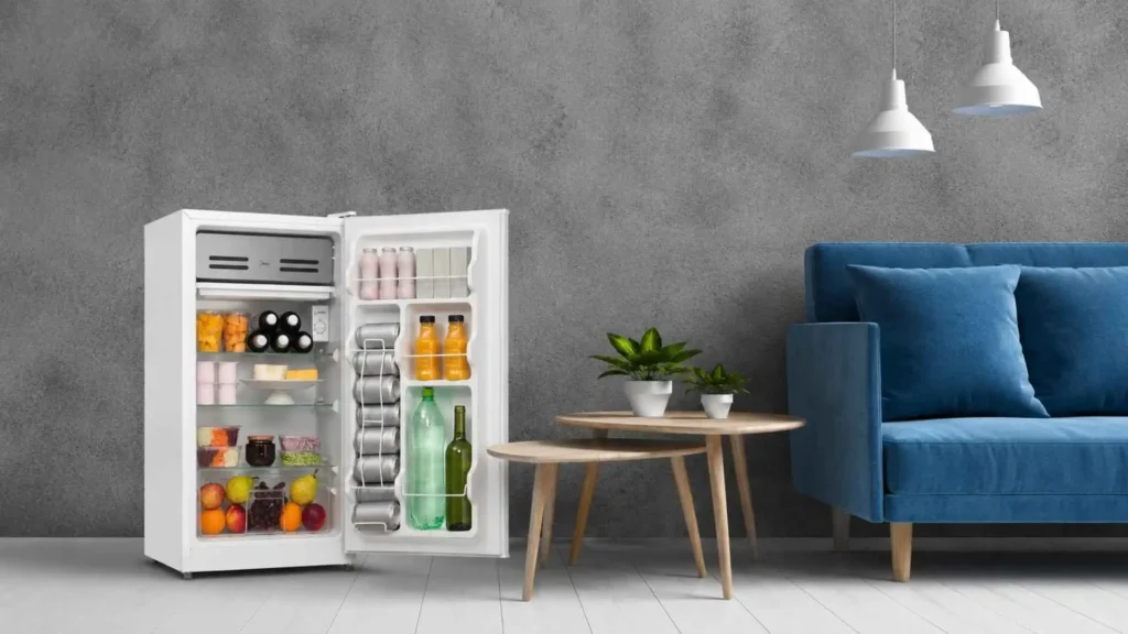 Visão interna do Frigobar Midea 93L aberto, mostrando as três prateleiras de vidro temperado, gaveta de frutas e bebidas organizadas