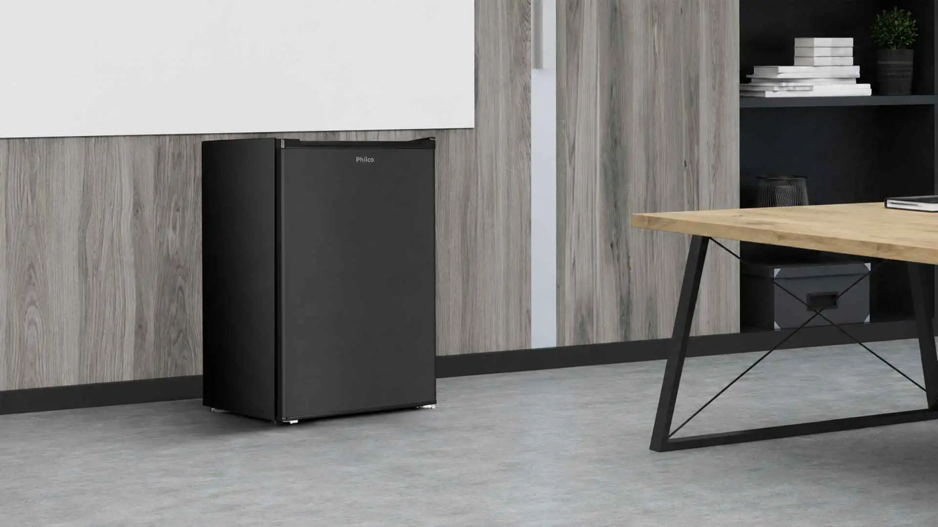 Frigobar Philco 68L PFG85P na cor preta instalado de forma compacta abaixo de um balcão em ambiente de escritório ou sala de estar