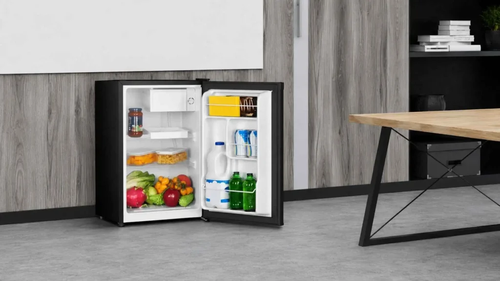 Visão interna do Frigobar Philco 68L PFG85P aberto e abastecido com frutas na gaveta inferior, latas de refrigerante e garrafas d'água na porta