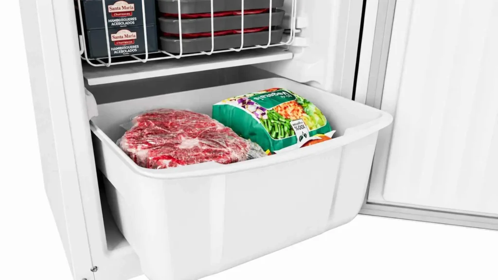 Visão interna do gavetão multiuso do freezer vertical Consul 189 litros CVU20 abastecido com pacotes de carne e vegetais congelados